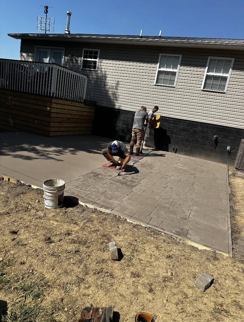 Complete Property Management crew installing a paver patio behind a home